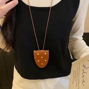 Gros plan d'un collier porte-lunettes rétro français à pois sur un mannequin en gilet.