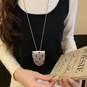 Détail d'un collier porte-lunettes rétro à pois, idéal comme chaîne de pull élégante.