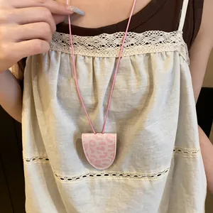 Vue détaillée d'un clip à lunettes rose léopard porté en collier rétro élégant.