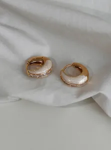 Close-up of French vintage gold hoop earrings with white glittery inlay and clear zircons