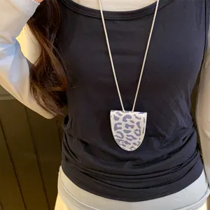 Vue détaillée d'un pendentif porte-lunettes léopard porté sur un haut noir comme collier.