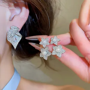 Gros plan de boucles d'oreilles fleurs argentées avec perles et zircons pavés scintillants.
