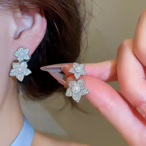 Détail d'élégantes boucles d'oreilles fleurs en argent avec zircons et perles, look luxe