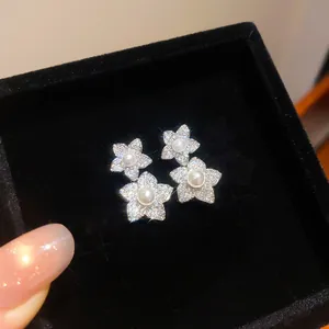 Gros plan de boucles d'oreilles fleurs élégantes avec zircons et centres perles