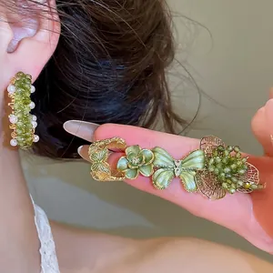 Elegant green forest style floral and butterfly earrings with crystal beads on a model.