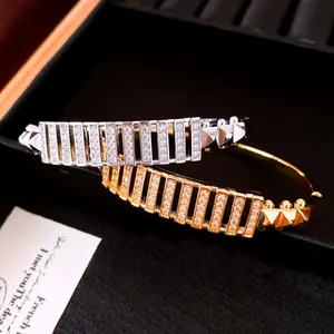 Dettaglio di bracciali placcati oro e argento con pavé di zirconi rettangolari scintillanti
