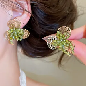 Gedetailleerde weergave van bosstijl oorbellen met groene kristallen en goudkleurige bloem