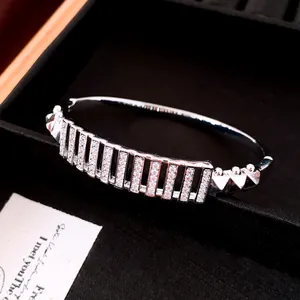 Primo piano di bracciale rigido placcato argento 18K con zirconi rettangolari.