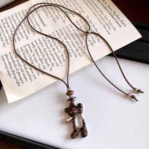 Gros plan d'un collier avec pendentif ours léopard et cordon en cuir marron vintage.