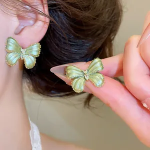 Elegante groene vlinder oorbellen met hartvormige kristallen op het oor en de hand