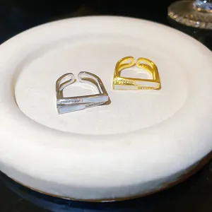 Detail view of two geometric open rings in gold and silver finish with shell inlay