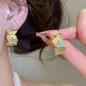 Close-up van elegante groene en gouden vlinder oorringen gedragen aan het menselijk oor