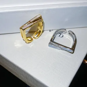 Close-up of elegant gold and silver square open rings with zircon and white shell inlay
