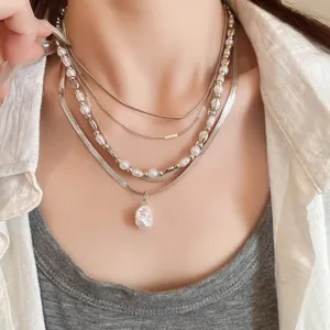 Detailaufnahme von mehrlagigen Silberhalsketten mit Barockperlen und feinen Perlenketten