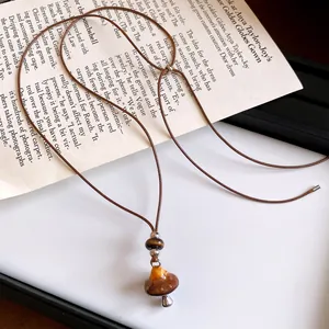 Détail macro du pendentif champignon vintage avec motif léopard sur cordon en cuir brun