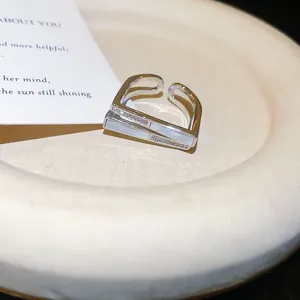 Close-up of minimalist silver square open ring with zircon and shell inlay details.