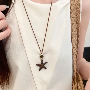 Gros plan d'un collier étoile de mer vintage avec pendentif léopard sur un cordon marron