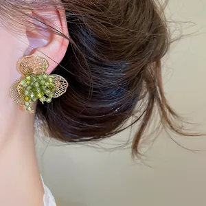 Detailopname van een delicate groene kristallen bloemenoorbel met gouden filigraan.