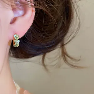 Gedetailleerde macro-opname van elegante lichtgroene bloemen oorringen met kristallen op het oor