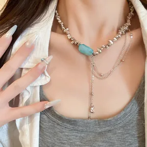 Detailansicht einer unregelmäßigen silbernen Perlenkette mit blauem Stein und Mondquasten