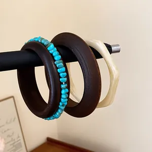 Close-up of retro Maillard style resin and wood bangle set on a black display rod