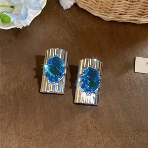 Detailweergave van elegante zilveren oorbellen met grote ovale blauwe zirkonen.