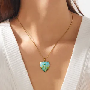 Gros plan détaillé d'un collier pendentif en forme de cœur avec émail floral bleu.