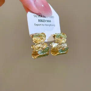 Detailweergave van goudkleurige vlinder-oorringen met groen emaille op een kaartje