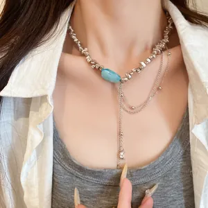 Detailaufnahme einer unregelmäßigen silbernen Perlenkette mit blauem Stein und Stern-Mond-Quasten