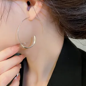 Nahaufnahme von minimalistischen silbernen spiralförmigen C-Creolen am Ohr des Models