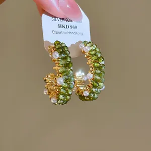 Detail van bosstijl groene kristallen en parel oorbellen met gouden finish