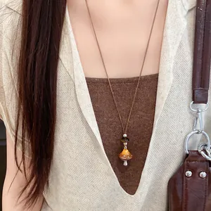 Collier vintage en corde de cuir avec un pendentif champignon orange porté par un modèle