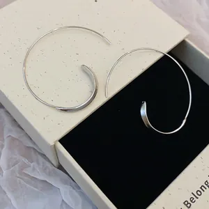 Detaillierte Nahaufnahme von silbernen C-förmigen Metallohrringen in einer Geschenkbox