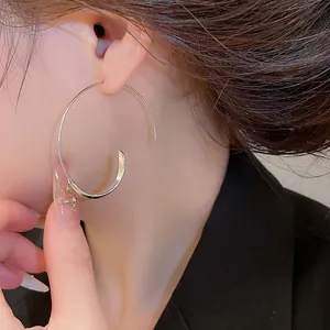 Detailansicht eines minimalistischen silbernen C-förmigen Creolen-Ohrrings am Ohr des Models