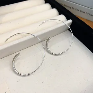 Nahaufnahme minimalistischer silberner C-Ring-Ohrringe auf weißem Schmuckständer