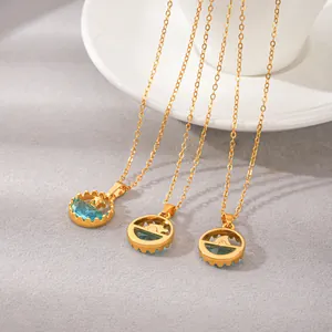 Vue détaillée des pendentifs en acier titane doré aux motifs marins et pierres bleues.