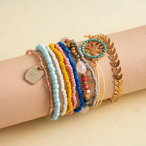 Gros plan d'un lot de 10 bracelets vintage en perles avec breloque feuille et arbre de vie.