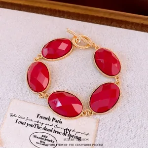 Elegant gold-tone bracelet with oval red resin stones and toggle clasp