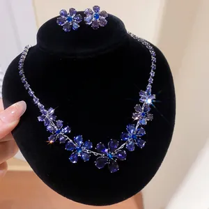 Close-up of elegant blue floral crystal necklace and earrings set on black velvet stand
