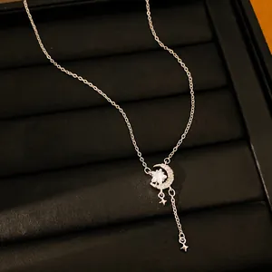 Detailopname van zilverkleurige ketting met maan- en sterhanger van zirkoon