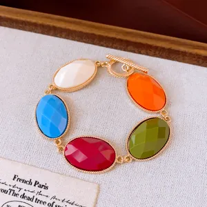 Detail van een chique goudkleurige armband met kleurrijke ovale harsstenen