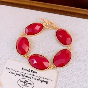 Macro-opname van rode ovale harsstenen op een gouden armband met toggle-sluiting