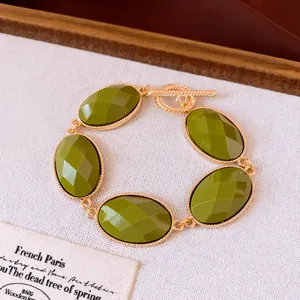 Detail van een luxe armband met olijfgroene gefacetteerde ovale stenen van hars.