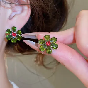 Close-up of floral stud earrings with green and red zircon crystals