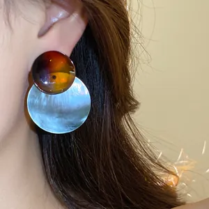 Detailansicht der Retro-Ohrstecker aus Acetat mit einem runden Muschelanhänger