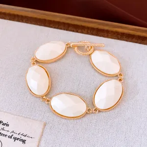 Gedetailleerd overzicht van gefacetteerde witte hars ovalen op gouden armband