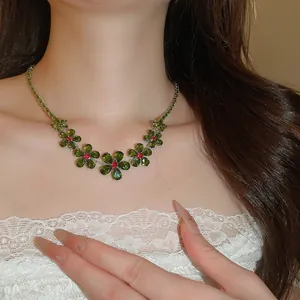 Close-up of a zirconia flower necklace featuring green stones and red crystal centers