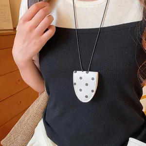 Detailansicht einer eleganten Lederkette mit Punkten und Brillenclip an einem Model.