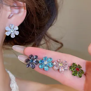Detailed view of sparkling flower earrings in white, blue, pink, and green zircon stones.