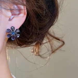 Close-up of elegant flower stud earring with purple and blue sparkling gemstones